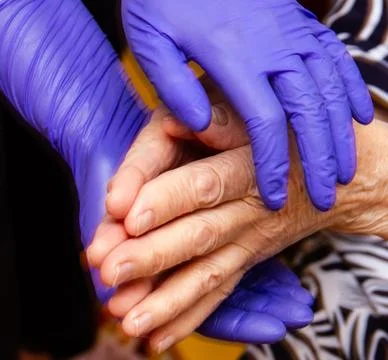Old man's hands support hands in medical gloves Stock Photos