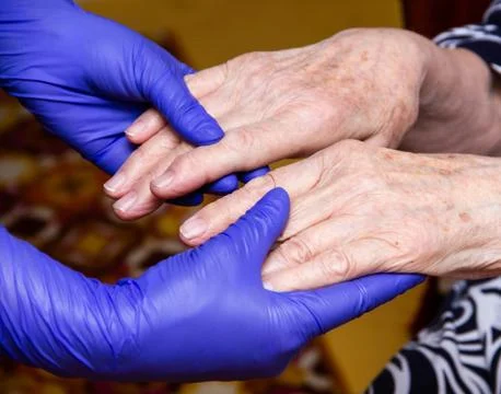 Old man's hands support hands in medical gloves Stock Photos