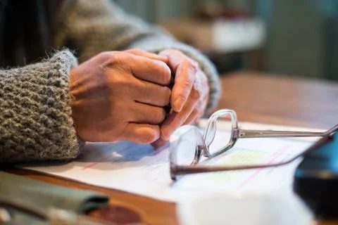 The old man's hands in a sweater on the table next to the glasses close-up. Stock Photos