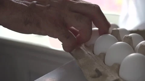 The old man's hands take chicken eggs from the container to cook food Stock Footage 253894334