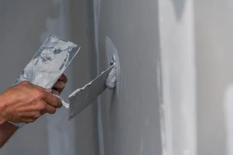 Old manual worker with wall plastering tools renovating house Stock Photos