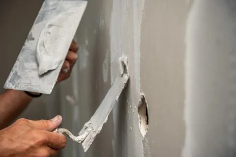 Old manual worker with wall plastering tools renovating house. Stock Photos