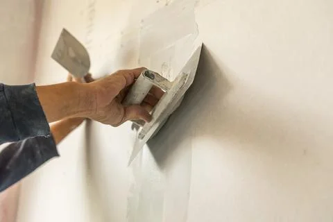 Old manual worker with wall plastering tools renovating house. Stock Photos