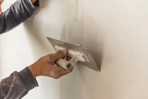 Old manual worker with wall plastering tools renovating house. Stock Photos
