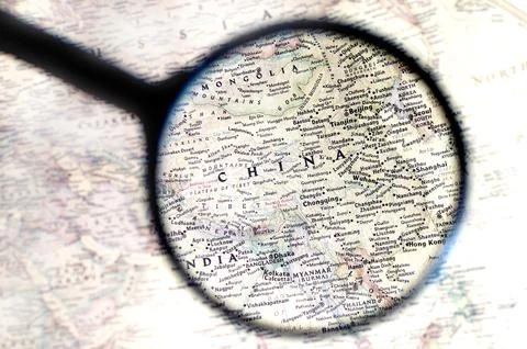 Old map with territory of China and name of country is enlarged through a m.. Stock Photos
