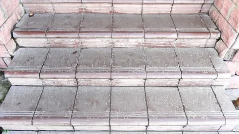 Old maroon stone steps covered with graphite with scratches and cracks Foto stock