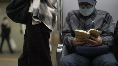 Old masked man reading book on Japanese Public Transport Train Subway Vídeo Stock 242604272
