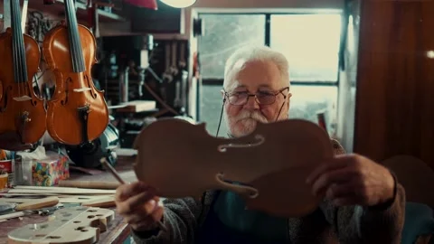 Old master holds in his hands the front part of the violin Stock Footage 167112852