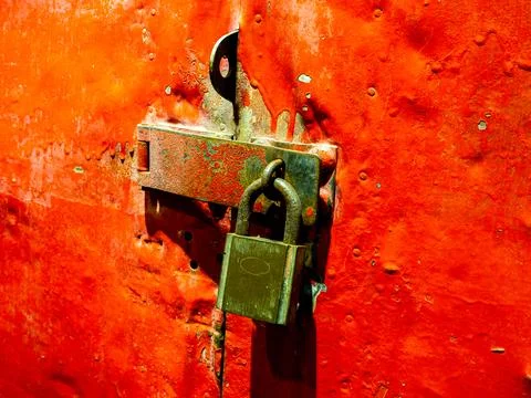 Old master key is lock on red steel door. An old rusted red iron door locked  Stock Photos