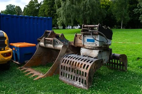 Old mechanical grapple loader on a green lawn next to construction equipment Stock Photos