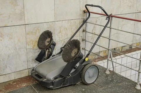 Old mechanical sweeping machine chained lock in a public place. Stock Photos