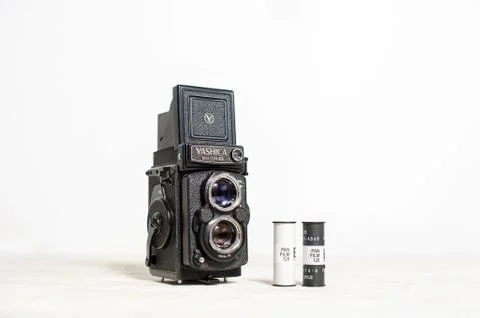 Old medium format film camera and photographic film stand on a table on a whi Stock Photos