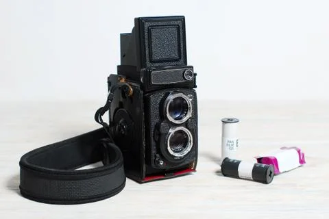 Old medium format film camera and photographic film stand on a table on a whi Stock Photos