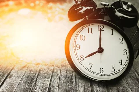 Old memory time concept, retro clock timed at 8 o'clock on wood with sun ligh Stock Photos