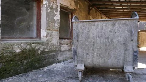 Old metal bin container next to abandoned buildings Stock-Fotos