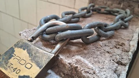 Old metal chain with a padlock. Rusty iron links secured with a weathered steel Stock Photos
