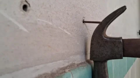 Old metal hammer pulling nail from concrete wall motion video Stock Footage 339247459