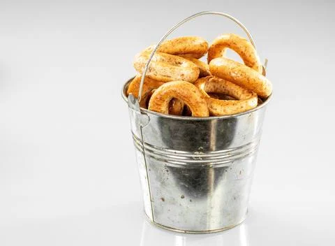 Old metal kitchen bucket with crispy bagels on a white background Stock Photos