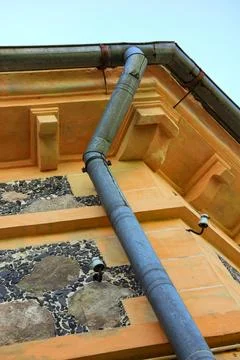 Old metal rain gutter and downpipe on historic stone facade Foto stock