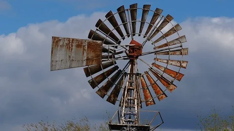 Old metal wind pump turning slowly in a breeze Stock Footage 106301031