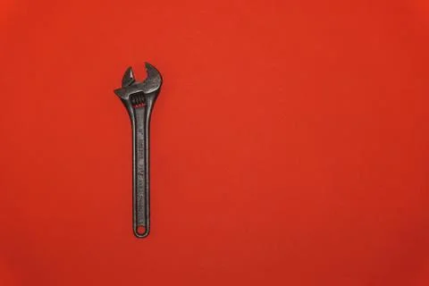 Old metal wrench on a red background Foto stock