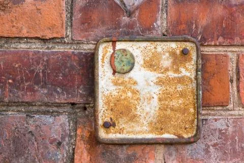 Old metallic red rusty plate on a brick wall Stock-Fotos