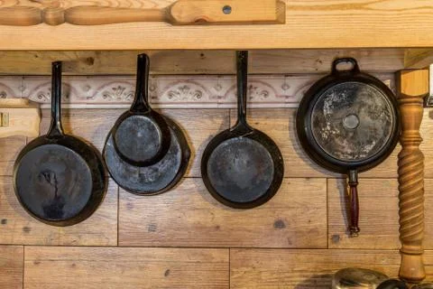 Old metallic rustic pans hanging on the wooden wall Stock Photos