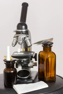 Old microscope and two dark bottles Stock Photos