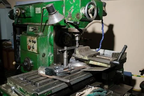 An old milling machine stands in a workshop, surrounded by various tools. Wor Foto stock