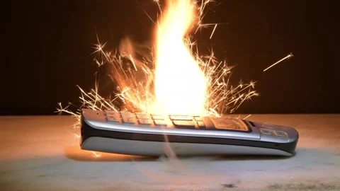 An old mobile phone explodes with a bright flash and sparks, demonstrating the d Video stock 309485349