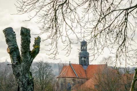 An old monastery in the background with trees and branches in the foreground Stock Photos