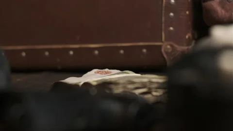 Old money is put on table next to black gun and brown leather suitcase. 1920s Stock Footage 150466864