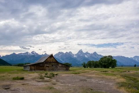 Old mormon barn farm in summer with blue colored grand tetons in background Stock Photos