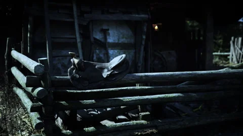 Old motorcycle resting on a rustic wooden fence near an abandoned barn at dusk Stock Footage 292533285