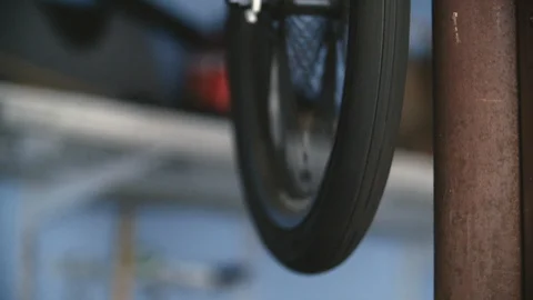 An old mountain bike's front tire spins freely while hanging in blue garage Stock Footage 100341336