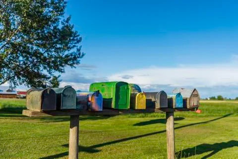 Old multi-coloured mailboxes stand on a board in a field Stock Photos