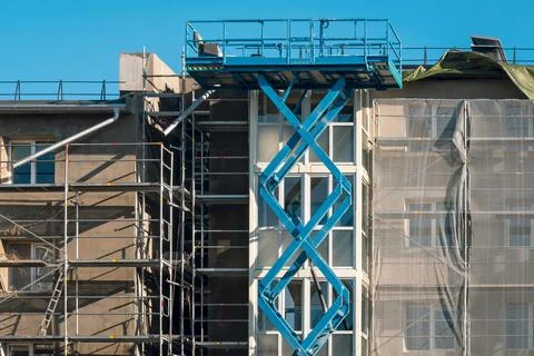 Old multistory facade repair using a high scissor lift with a platform Stock Photos
