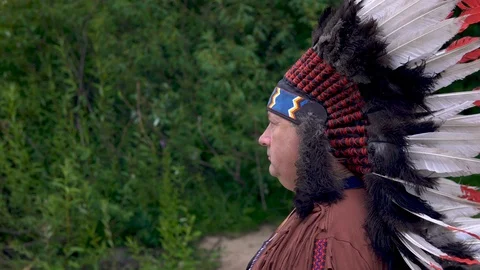 Old Native American Indians stands against the background of the forest with a Stock Footage 113355558
