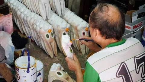 Old native vietnamese man sitting on ground and painting handmade masks in hanoi Stock Footage 147372968