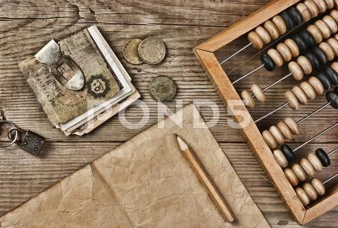 Old notes and coins and abacus on a wooden table Stock Photos