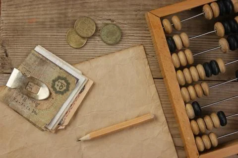 Old notes and coins and abacus on a wooden table Stock Photos