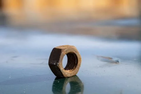 Old Nut Sits on a Metal Surface With Blurred Background Showing Hints of Li.. Stock Photos