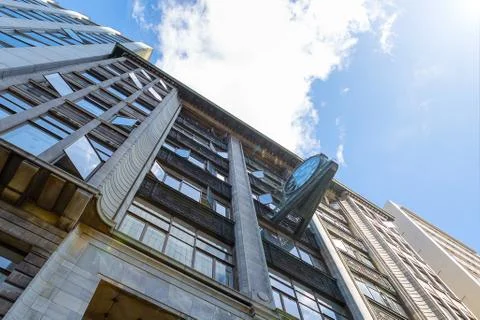 Old office building facade with clock and cloudy sky Stock Photos