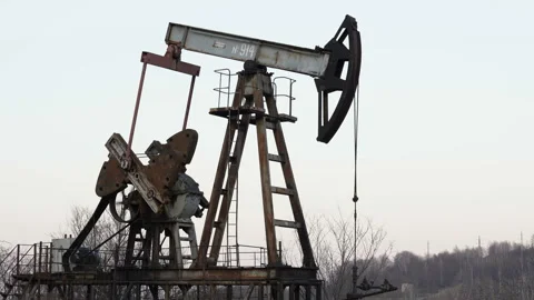 Old Oil Well Pump Jack Extracting Petroleum. Working Oil Pump Jack Against  Stock Footage 127798932