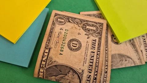 Old one dollar bills resting on bright colorful sticky note pads Stock Photos