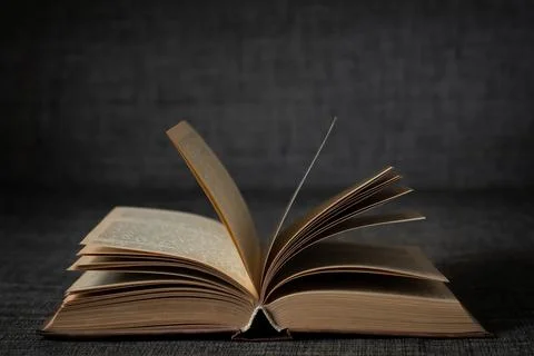 Old open book on a dark background close-up Stock Photos