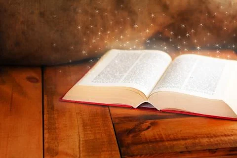 Old open book with magic light on wooden table Stock Photos