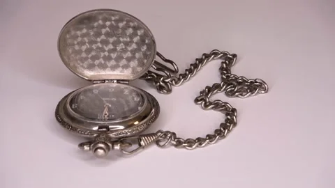 An old opened pocket watch on a silver chain slowly turns in a circle - loop  Video stock 169292805