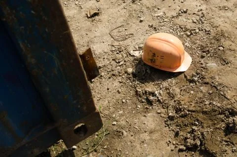 Old orange construction helmet lying on the ground after construction Stock Photos