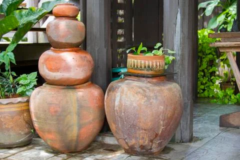Old orange earthen jars stacked next to a wooden pole. Foto stock